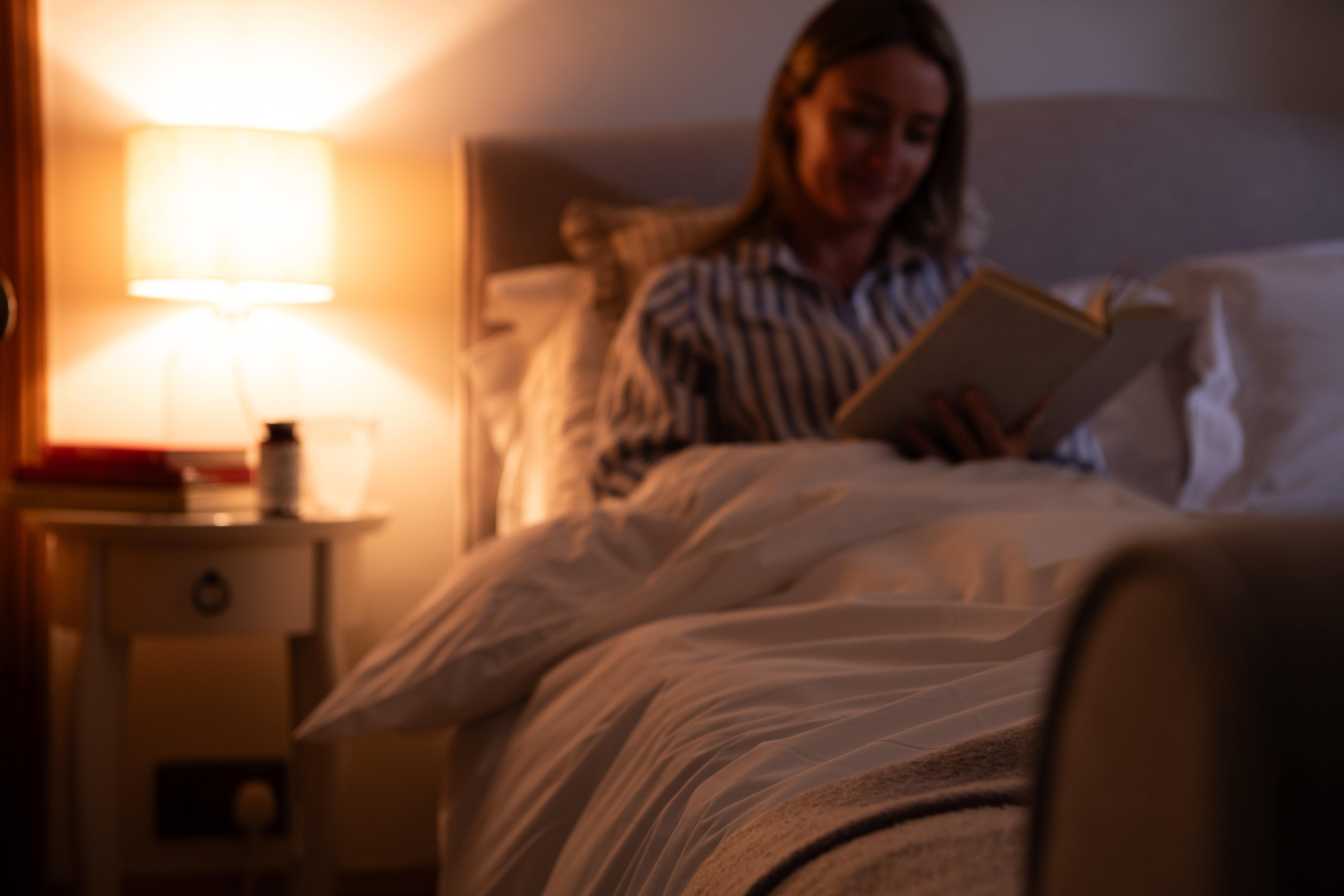 Young woman working on a laptop at a desk surrounded by books and papers